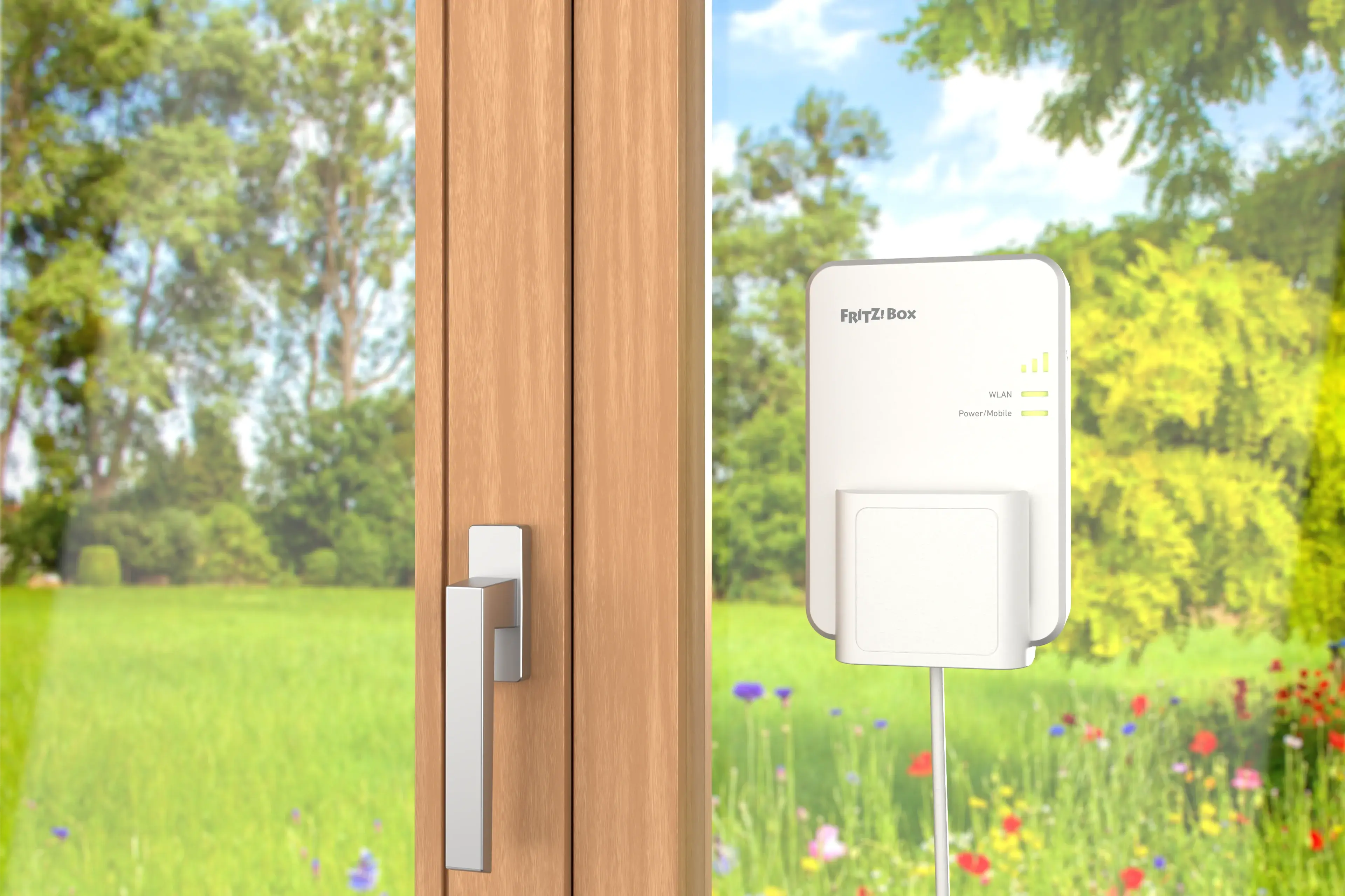 Fritz!Box WLAN-Repeater an einem Holzfenster in einer blühenden Wiese installiert.