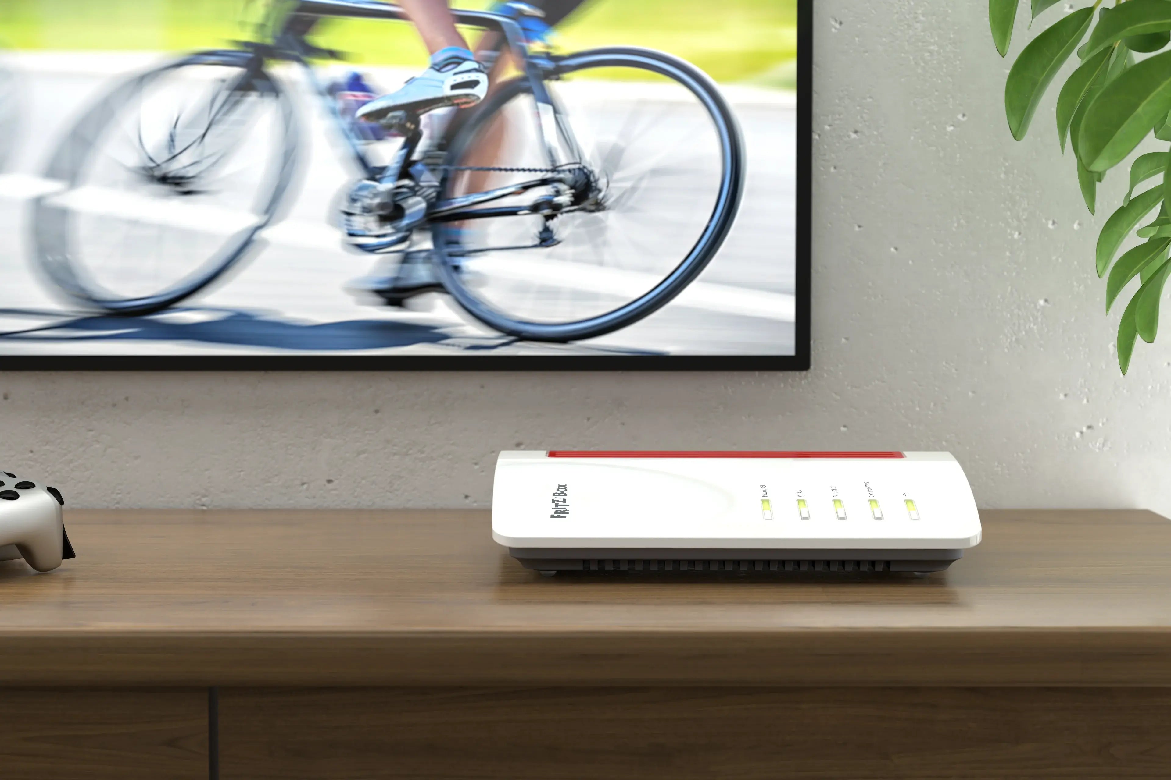Moderne WLAN-Router auf einem Tisch, mit einem Fahrradfahrer auf dem Bildschirm im Hintergrund.